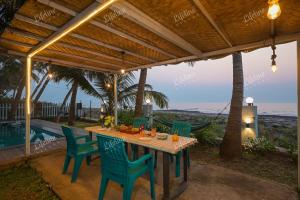 une table et des chaises sur une terrasse avec la plage dans l'établissement En-Ocean Luxurious Infinity Pool Villa Overlooking Sea And Beach Touch, à Alibaug