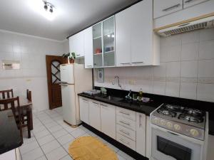a kitchen with white cabinets and a white refrigerator at Espaço da Paz e Serenidade in Praia Grande