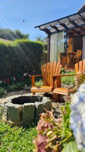 a garden with two wooden chairs and a fire pit at Chalés Leopoldo em Monte Verde in Monte Verde