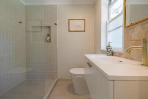 a bathroom with a shower and a toilet and a sink at Hibiscus Cottage in Ballina