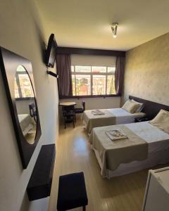 a hotel room with two beds and a mirror at Hotel Franco Blumenau in Blumenau