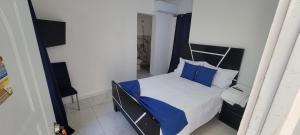 ein Schlafzimmer mit einem Bett mit blauen Kissen in der Unterkunft Hostal y Piscina in La Romana