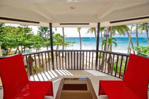 een balkon met rode stoelen en uitzicht op het strand bij La Suerte Villa in Boracay