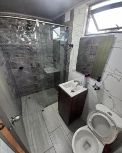 een badkamer met een douche, een toilet en een wastafel bij Hotel Atheron suite La Magia de Zipaquirá in Zipaquirá