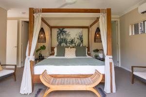 ein Schlafzimmer mit einem Himmelbett mit einem Holzrahmen in der Unterkunft Escapades @ Palm Cove in Palm Cove