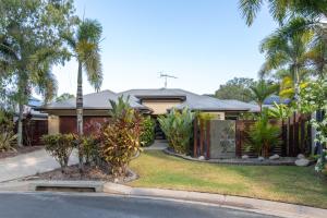 a house with a fence and palm trees at Escapades @ Palm Cove in Palm Cove