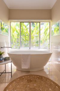 eine Badewanne im Bad mit einem großen Fenster in der Unterkunft Escapades @ Palm Cove in Palm Cove + 37 Fotos