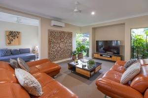 a living room with leather furniture and a flat screen tv at Escapades @ Palm Cove in Palm Cove