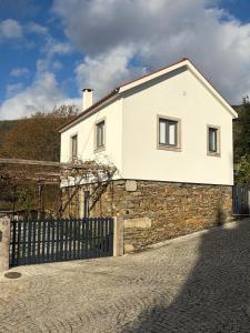 a white house on a stone wall with a fence at Quinta do Passal - Country house in Parada de Ester
