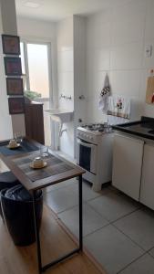 a kitchen with a stove and a table in it at APTO EASY Poços de Caldas in Poços de Caldas