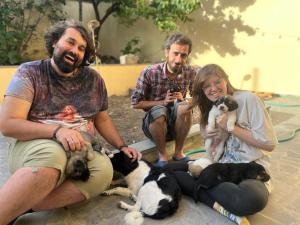 een groep van drie mensen die naast een groep honden zitten bij Noah's sunlight villa hostel in Jerevan