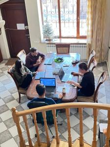 een groep mensen die rond een tafel met laptops zitten bij Noah's sunlight villa hostel in Jerevan
