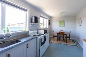 une cuisine avec un évier et une cuisinière four supérieur dans l'établissement Foxton Beach Bach 5 Star Location 2 Min Walk To Beach New Furnishings BBQ, à Foxton Beach