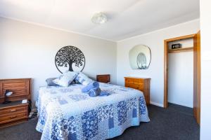 une chambre avec un lit avec un couvre-lit bleu et blanc dans l'établissement Foxton Beach Bach 5 Star Location 2 Min Walk To Beach New Furnishings BBQ, à Foxton Beach
