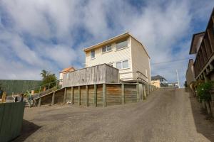 une maison sur une clôture en bois au bord d'un chemin de terre dans l'établissement Foxton Beach Bach 5 Star Location 2 Min Walk To Beach New Furnishings BBQ, à Foxton Beach