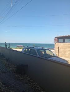 un'auto parcheggiata accanto a un muro vicino alla spiaggia di Flats Beira mar casal a Penha 1 altra foto