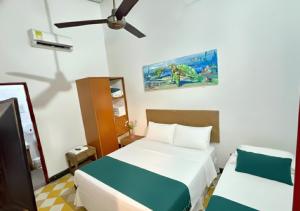 een slaapkamer met twee bedden en een plafondventilator bij Hotel Casa de Sarah in Santa Marta
