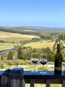 two wine glasses sitting on a table with a bottle of wine at Serendeva: Stunning views, private & EV charger in Denmark