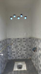 a bathroom with a toilet with three windows on the wall at Vila's Homestay in Kohīma