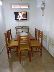 a dining room table and chairs with a tv on the wall at Casa ruau in Valeria del Mar