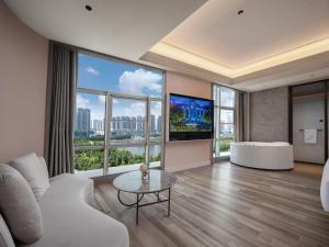 a living room with a couch and a large window at Mercure Luoyang Downtown in Luoyang