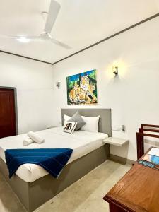een slaapkamer met een bed met een schilderij aan de muur bij Hiri Point Villa in Dikwella