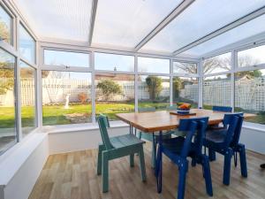 une véranda avec une table en bois, des chaises et des fenêtres dans l'établissement Merlin's Retreat, à Tintagel