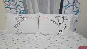zwei Kissen mit der Zeichnung eines Paares auf einem Bett in der Unterkunft Beutiful New Villa In Punta Cana in Punta Cana