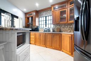 une cuisine avec des armoires en bois et un réfrigérateur en acier inoxydable dans l'établissement The Dorset on Ashby, à Chaguanas Village