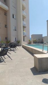 a row of chairs next to a building with a swimming pool at APTO EASY Poços de Caldas in Poços de Caldas