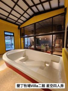 une grande baignoire blanche dans une pièce avec une grande fenêtre dans l'établissement 墾丁牧場Villa Kenting Pasture - Villa B&B, à Kenting