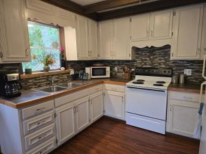 La cuisine est équipée de placards blancs et d'un four avec plaques de cuisson blanches. dans l'établissement Hummingbird Hideaway - Lake Pets Hike Fish, à Hidetown