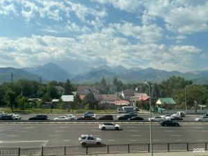 a parking lot with cars on a highway with mountains at Mosh Mosh Boutique Hotel in Almaty