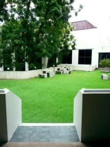 een groene tuin met banken voor een gebouw bij Royal Diamond Hotel in Phetchaburi