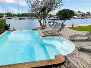 a swimming pool with chairs and a body of water at Villa lagon bleu in Le Gosier