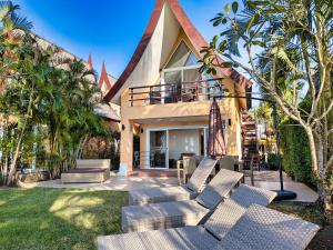 a house with a bunch of chairs in the yard at Five Palms Beachfront Villa - by KohChangVillas in Ko Chang