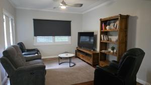 a living room with two chairs and a flat screen tv at 2 Long between breaks in Coffs Harbour