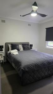 a bedroom with a bed with a ceiling fan at 2 Long between breaks in Coffs Harbour