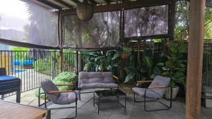 a patio with chairs and a couch and plants at 2 Long between breaks in Coffs Harbour