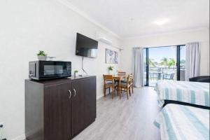 a hotel room with a bedroom with a bed and a television at The Anchorage Escape Studio - Steps away from City, Ferry and Stadium in Townsville in Townsville
