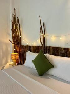 - une chambre avec un lit blanc et un oreiller vert dans l'établissement Papaya Hikkaduwa, à Hikkaduwa