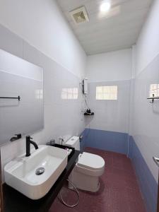 a white bathroom with a sink and a toilet at For Rest Inn in Phumĭ Réach Born (2)