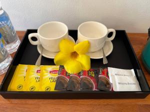 a tray with two cups and a flower on a table at For Rest Inn in Phumĭ Réach Born (2)