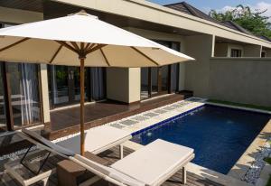 a swimming pool with a white umbrella and chairs and a house at SVARGA RENJANA ViLLA in Lombok