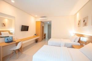 a hotel room with two beds and a desk with a computer at Hilani Boutique Hotel in Luengbata