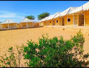 eine Reihe gelber Häuser in der Wüste in der Unterkunft Desert Villa Resort & Camp Jaisalmer in Jaisalmer