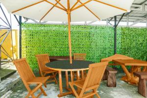 a table with chairs and an umbrella in front of a green wall at Hotel O Roda Inn in Padang