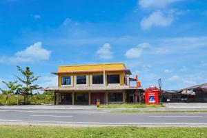 a building with a red phone booth next to a street at Hotel O Roda Inn in Padang