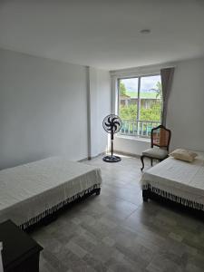 una camera da letto con due letti, una finestra e una sedia di Alpha1 a Roldanillo