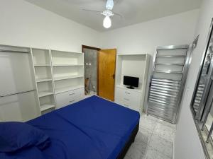 a bedroom with a blue bed and white shelves at Villa Caraguá Apartamentos in Caraguatatuba